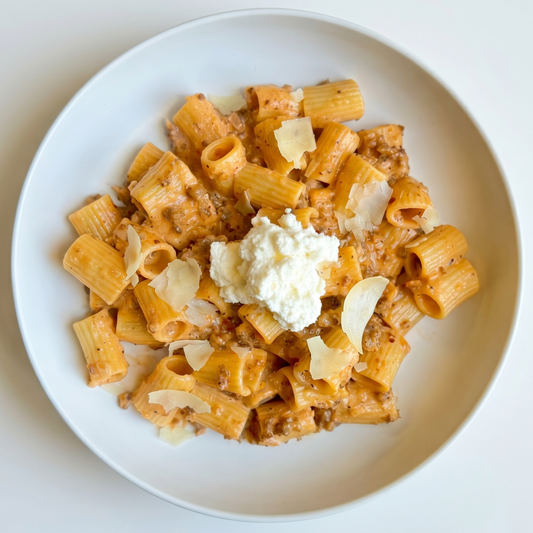 Plate of pasta with a scoop of ricotta cheese on a white background